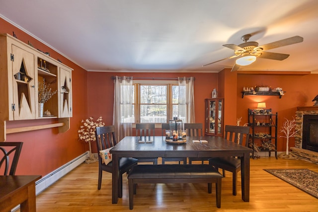 dining space featuring a fireplace, ceiling fan, light hardwood / wood-style flooring, and a baseboard radiator