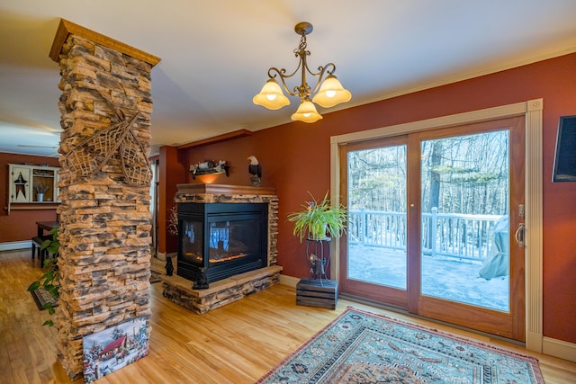 living room with crown molding, wood-type flooring, a fireplace, and a chandelier