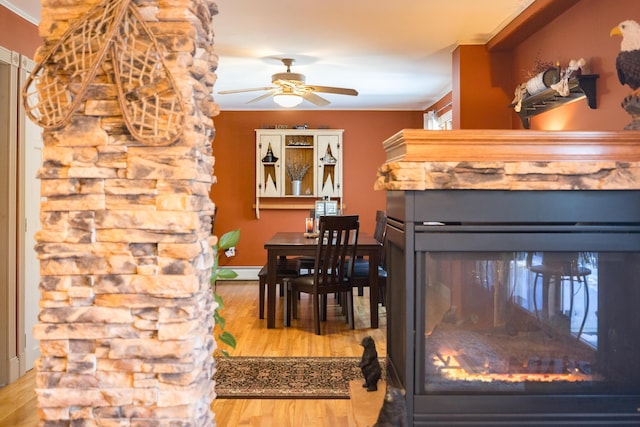 dining space with ceiling fan, a baseboard heating unit, crown molding, a fireplace, and hardwood / wood-style floors