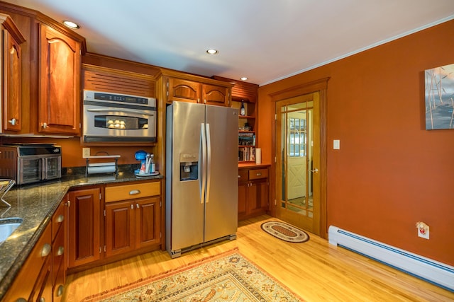 kitchen featuring dark stone countertops, light wood-type flooring, baseboard heating, appliances with stainless steel finishes, and ornamental molding