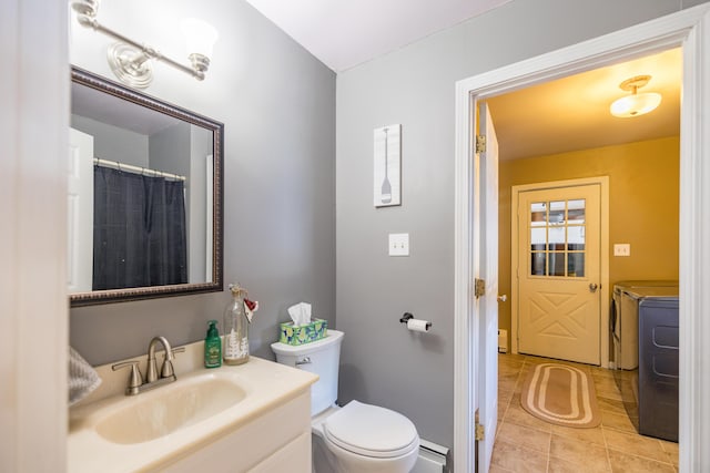 bathroom featuring a baseboard heating unit, tile patterned floors, toilet, vanity, and washer and dryer