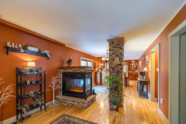 living room featuring ornate columns, built in features, wood-type flooring, and a fireplace