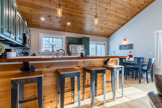 kitchen featuring decorative light fixtures, wooden ceiling, and stainless steel appliances