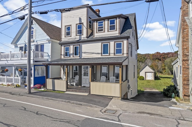 townhome / multi-family property with covered porch, a front yard, and roof with shingles