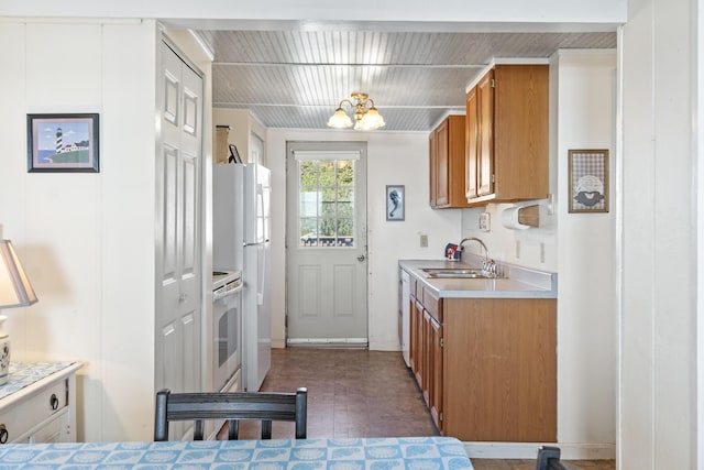 kitchen featuring light countertops, dishwashing machine, an inviting chandelier, brown cabinetry, and a sink