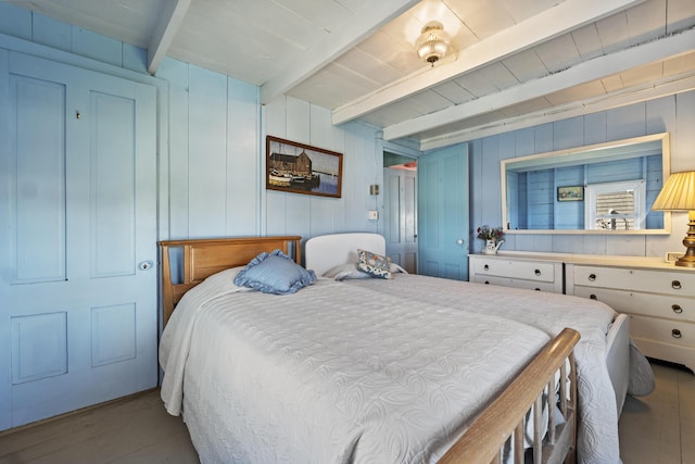 bedroom with beam ceiling and wood finished floors