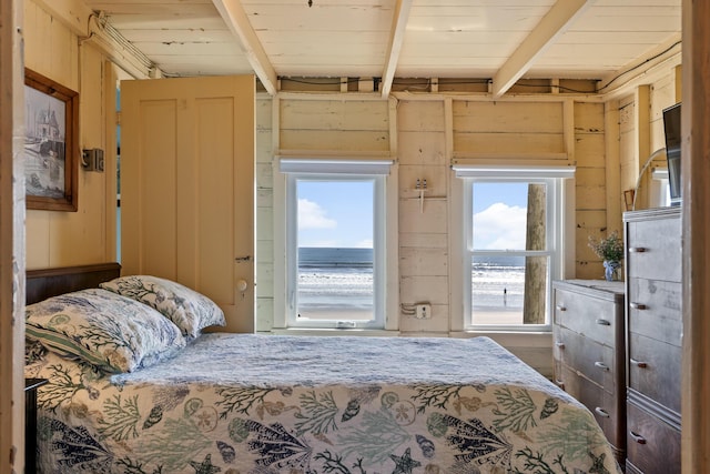 bedroom with beam ceiling, wooden ceiling, and wood walls