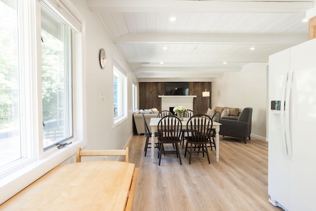 dining area with light wood-type flooring, wooden ceiling, and beamed ceiling