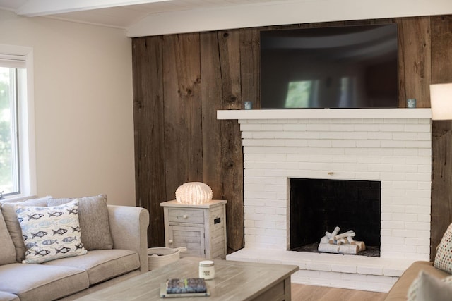 living room featuring light wood-type flooring, a brick fireplace, and plenty of natural light