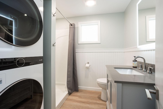 bathroom featuring a shower with curtain, hardwood / wood-style flooring, stacked washing maching and dryer, and toilet