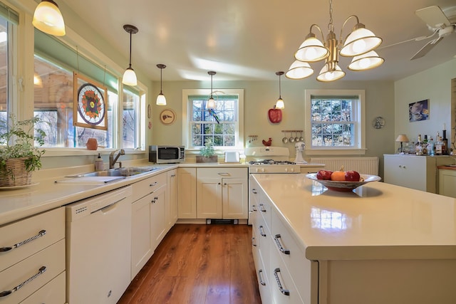 kitchen with sink, decorative light fixtures, dishwasher, dark hardwood / wood-style floors, and white cabinetry