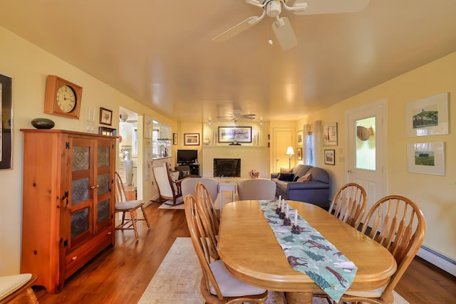 dining space with hardwood / wood-style floors, ceiling fan, plenty of natural light, and baseboard heating