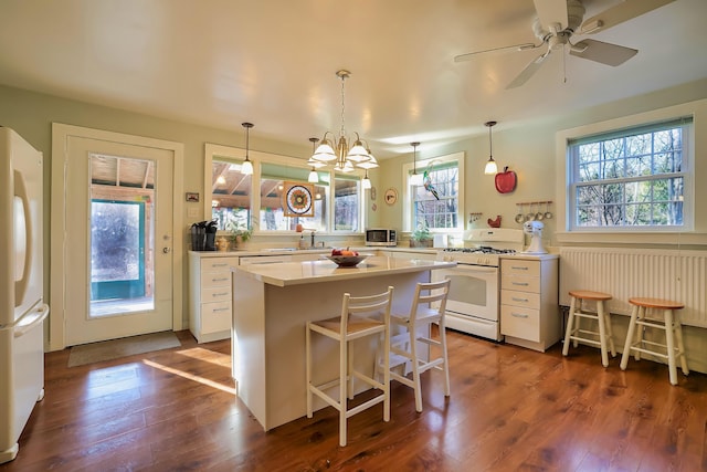 kitchen with pendant lighting, a breakfast bar, dark hardwood / wood-style floors, and white appliances