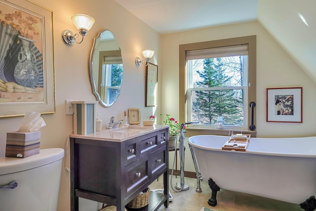 bathroom with a washtub, toilet, vanity, and vaulted ceiling