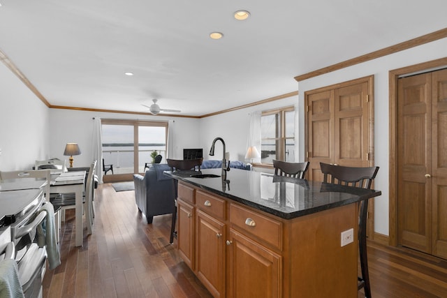 kitchen with a kitchen breakfast bar, ceiling fan, stainless steel electric stove, a center island, and dark hardwood / wood-style floors