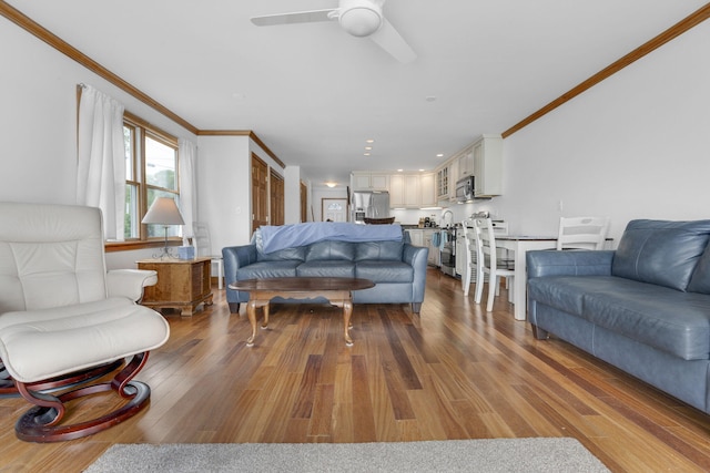 living room featuring hardwood / wood-style floors, ceiling fan, and crown molding