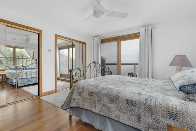 bedroom with ceiling fan, wood-type flooring, and two closets