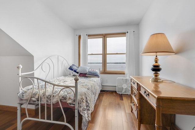 bedroom with baseboard heating and hardwood / wood-style flooring