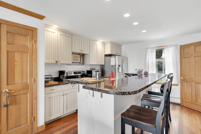 kitchen featuring a breakfast bar, stainless steel appliances, a kitchen island, and hardwood / wood-style flooring