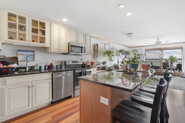 kitchen with ceiling fan, sink, light hardwood / wood-style flooring, an island with sink, and appliances with stainless steel finishes