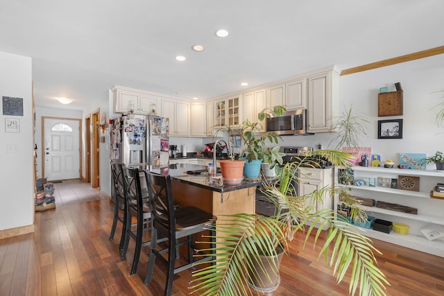 kitchen with a breakfast bar, cream cabinets, ornamental molding, dark hardwood / wood-style flooring, and kitchen peninsula