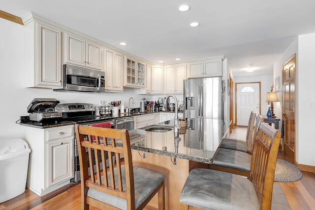 kitchen featuring a breakfast bar area, sink, stainless steel appliances, and light hardwood / wood-style floors