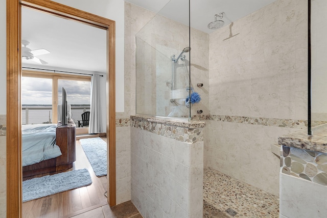 bathroom featuring hardwood / wood-style floors, ceiling fan, and a tile shower