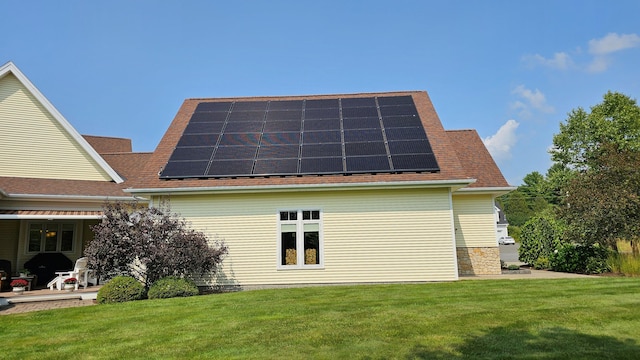 back of property featuring a lawn and solar panels