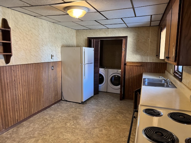 kitchen featuring sink, white fridge, a drop ceiling, and wood walls