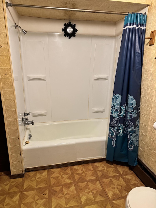 bathroom with shower / bath combo with shower curtain, parquet floors, and toilet