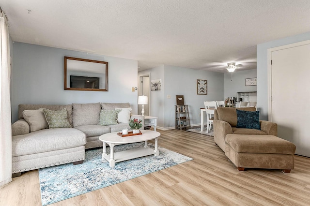 living room with ceiling fan, light hardwood / wood-style floors, and a textured ceiling