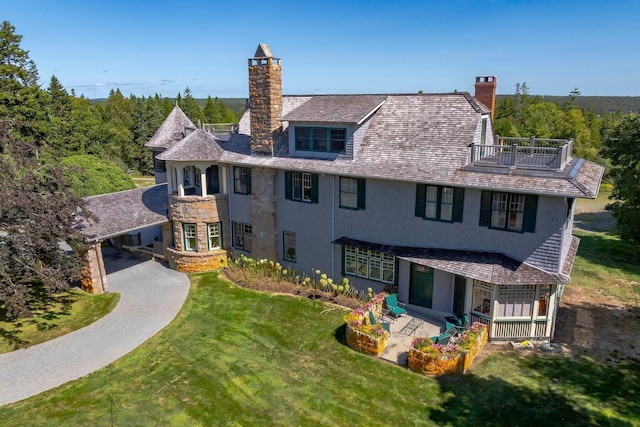 back of house with a yard and a balcony