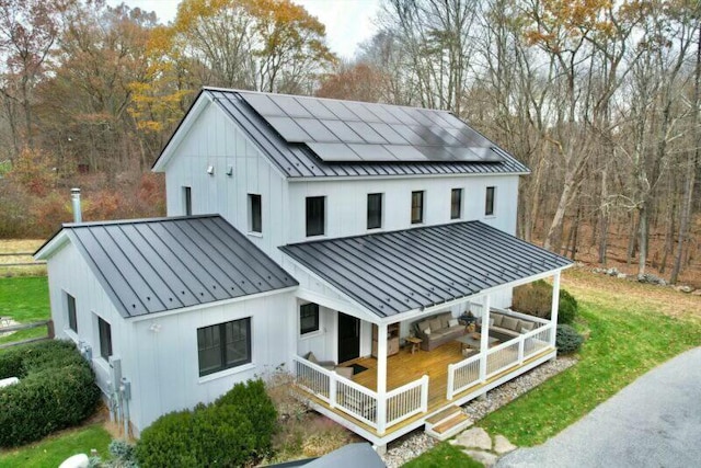 rear view of house with covered porch and solar panels