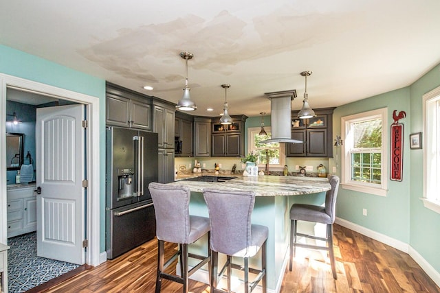 kitchen with dark brown cabinetry, dark wood-type flooring, high end refrigerator, decorative light fixtures, and island range hood