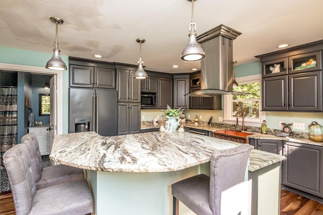 kitchen featuring a center island, dark hardwood / wood-style floors, decorative light fixtures, light stone counters, and stainless steel appliances