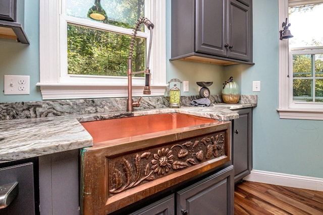 bar featuring gray cabinetry, light stone counters, and dark wood-type flooring