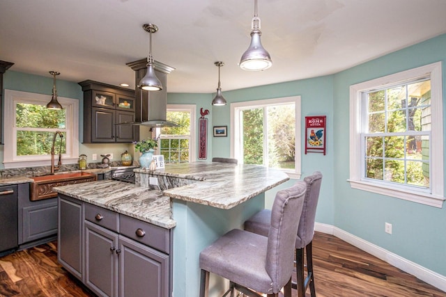 kitchen featuring gray cabinets, light stone counters, a kitchen island, and sink