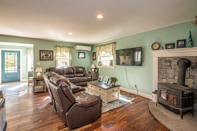 living room with a wood stove, dark wood-type flooring, a wealth of natural light, and a wall mounted AC