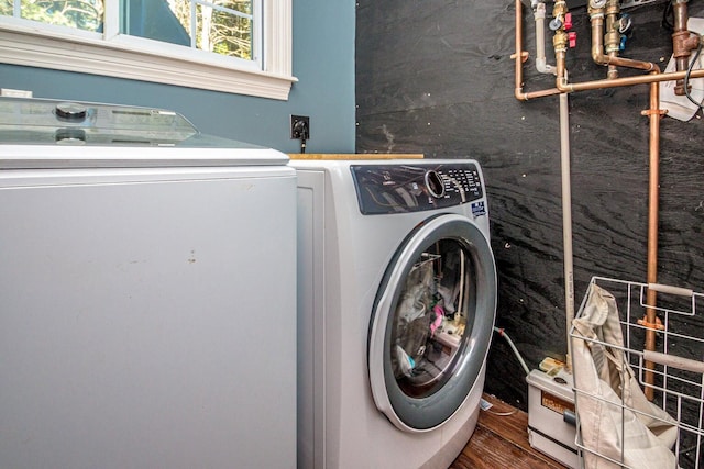 clothes washing area with washer and clothes dryer and dark wood-type flooring