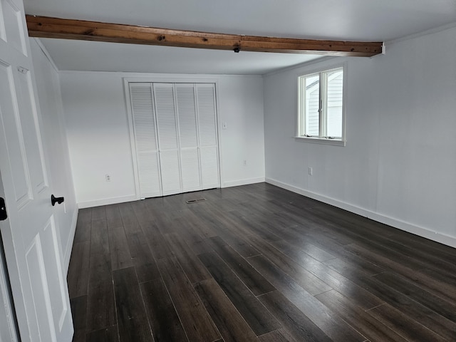 unfurnished bedroom with beamed ceiling, dark wood-type flooring, and a closet