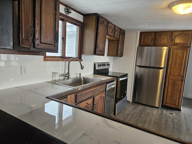 kitchen featuring appliances with stainless steel finishes, dark brown cabinetry, a textured ceiling, and sink