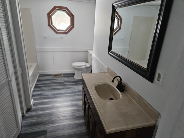 bathroom featuring a washtub, toilet, vanity, and hardwood / wood-style flooring