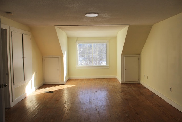 bonus room with hardwood / wood-style floors, a textured ceiling, and lofted ceiling