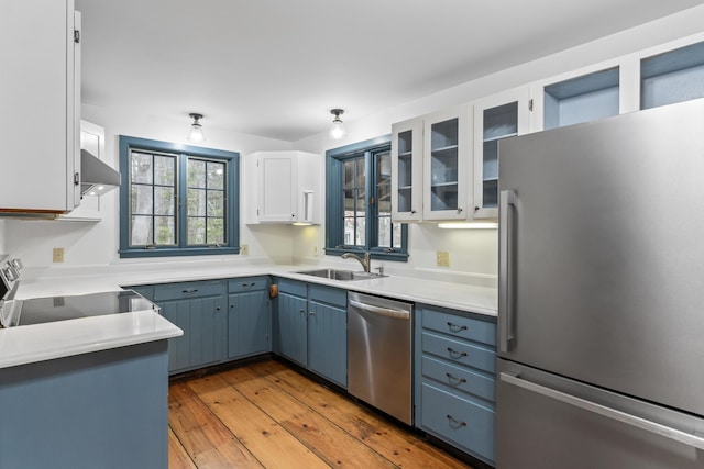 35 Cushman Rd, Nobleboro, ME 04555 - kitchen featuring range hood, stainless steel appliances, a sink, light wood-type flooring, and blue cabinets