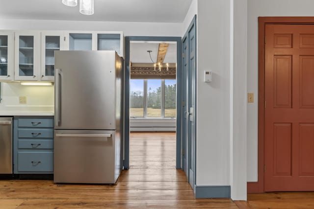 35 Cushman Rd, Nobleboro, ME 04555 - kitchen featuring wood finished floors, glass insert cabinets, baseboard heating, stainless steel appliances, and an inviting chandelier
