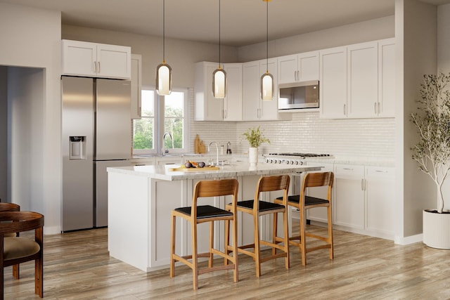 kitchen featuring white cabinets, decorative light fixtures, and stainless steel appliances