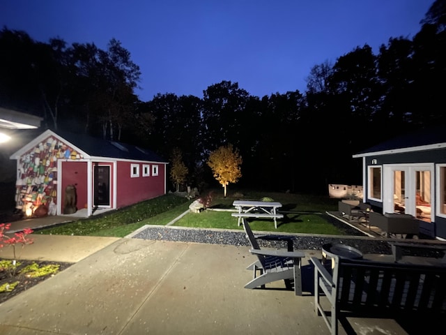 patio at twilight featuring a yard and an outdoor structure