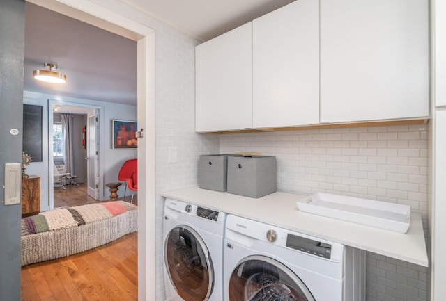 laundry area with cabinets, washer and dryer, and light hardwood / wood-style flooring