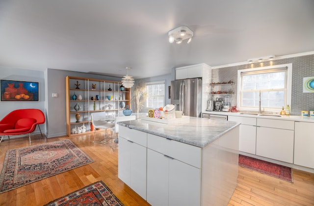 kitchen with a kitchen island, white cabinetry, sink, light hardwood / wood-style floors, and stainless steel refrigerator with ice dispenser