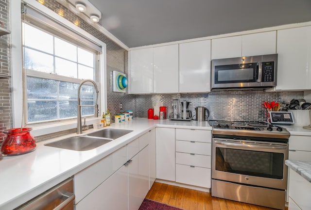 kitchen with white cabinetry, sink, decorative backsplash, and stainless steel appliances